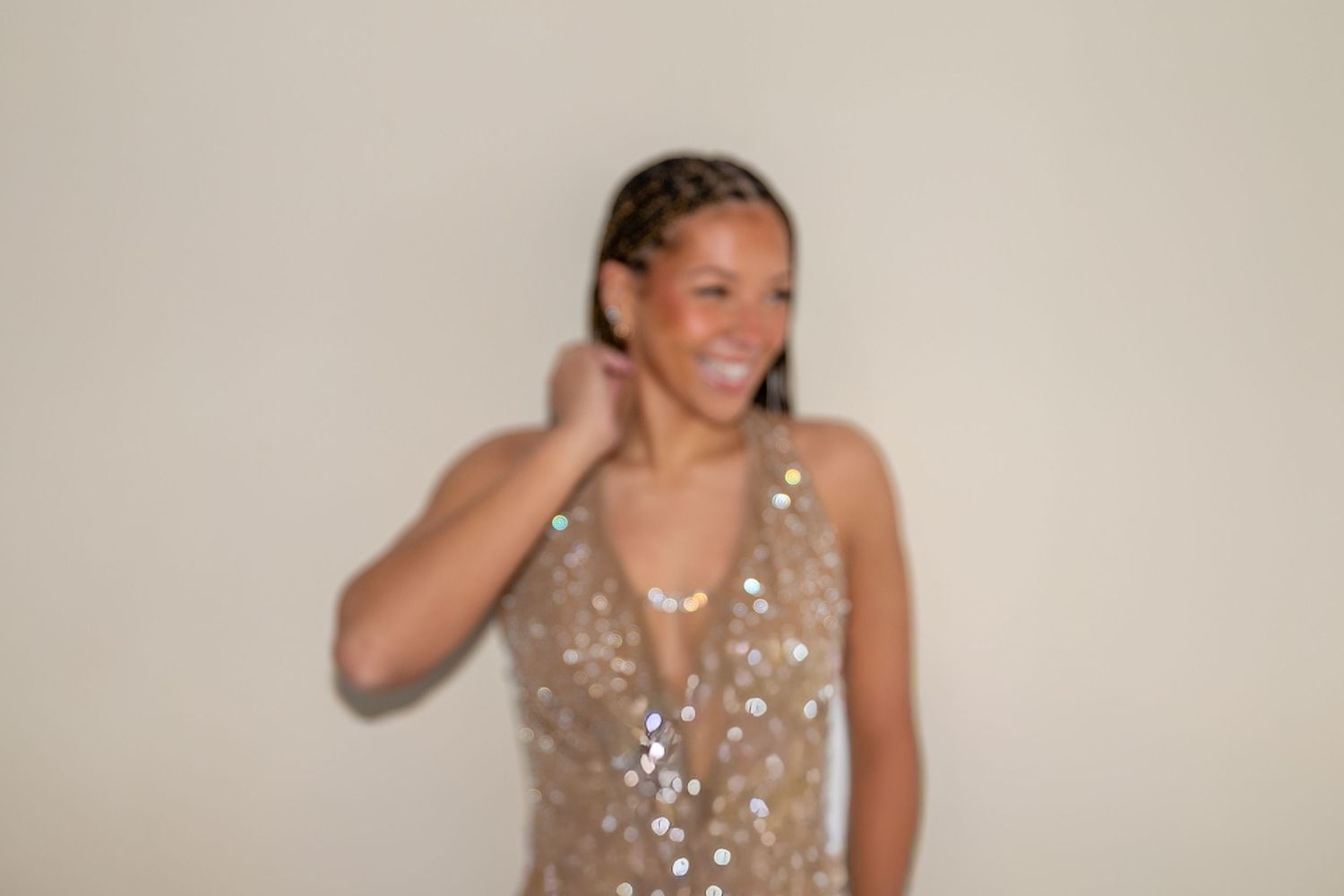 Young woman in a sparkling sequined dress posing against a neutral background.