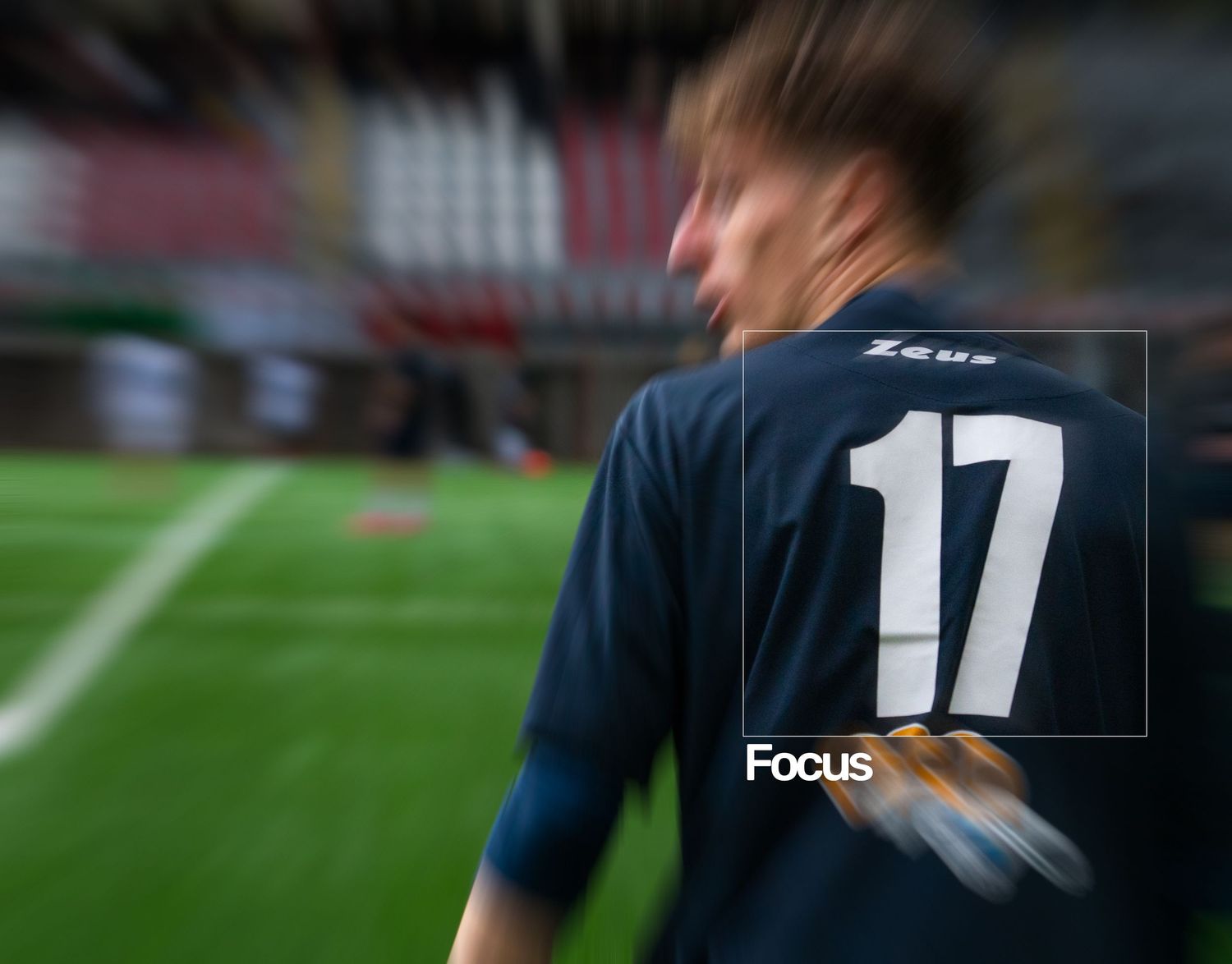 Soccer player wearing navy blue Zeus jersey number 17 on a stadium field, captured with motion blur effect.