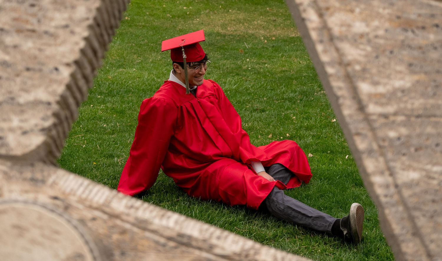 a unm graduate sitting on grass
