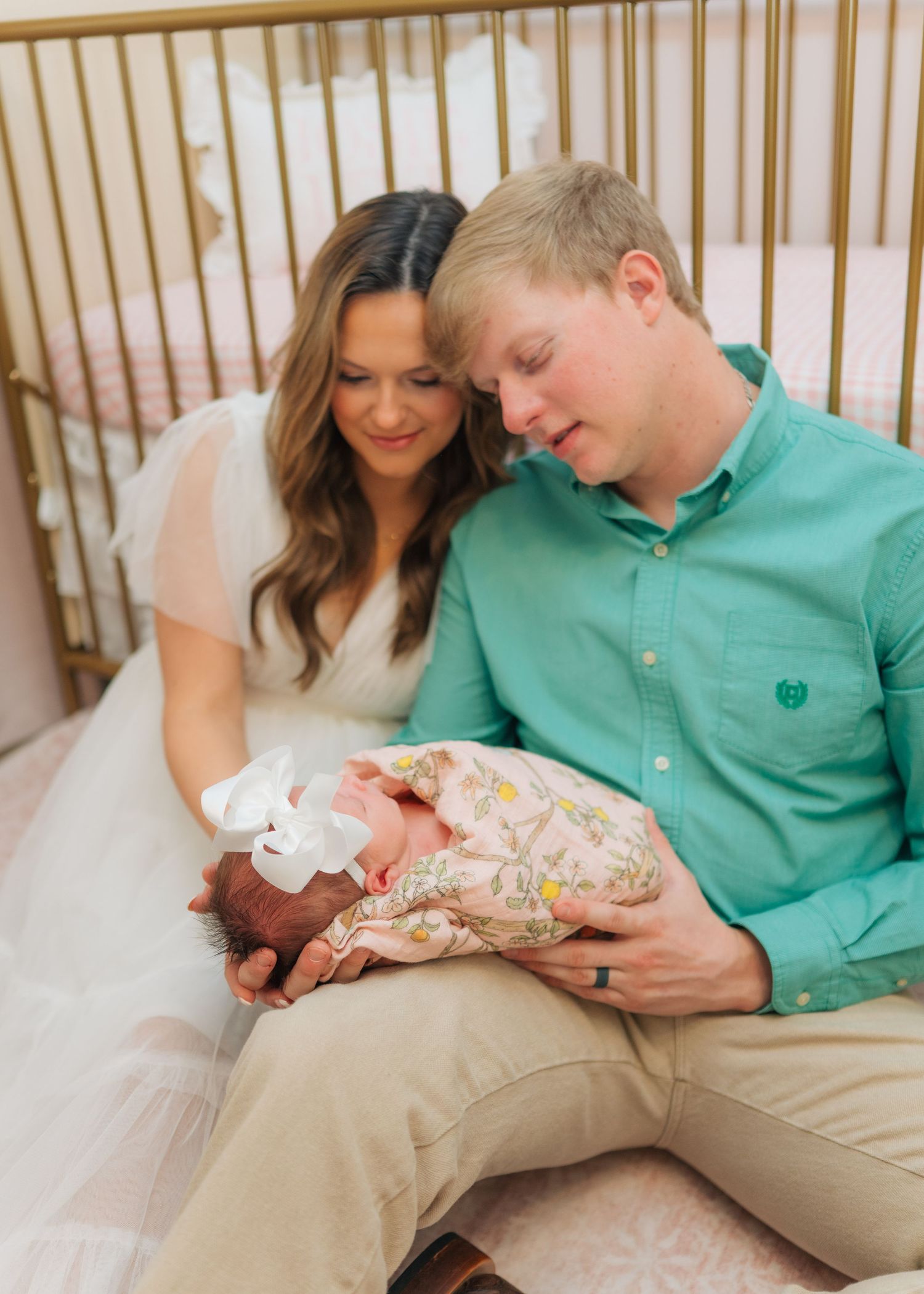 New parents lovingly gaze at their newborn baby girl in a nursery setting.