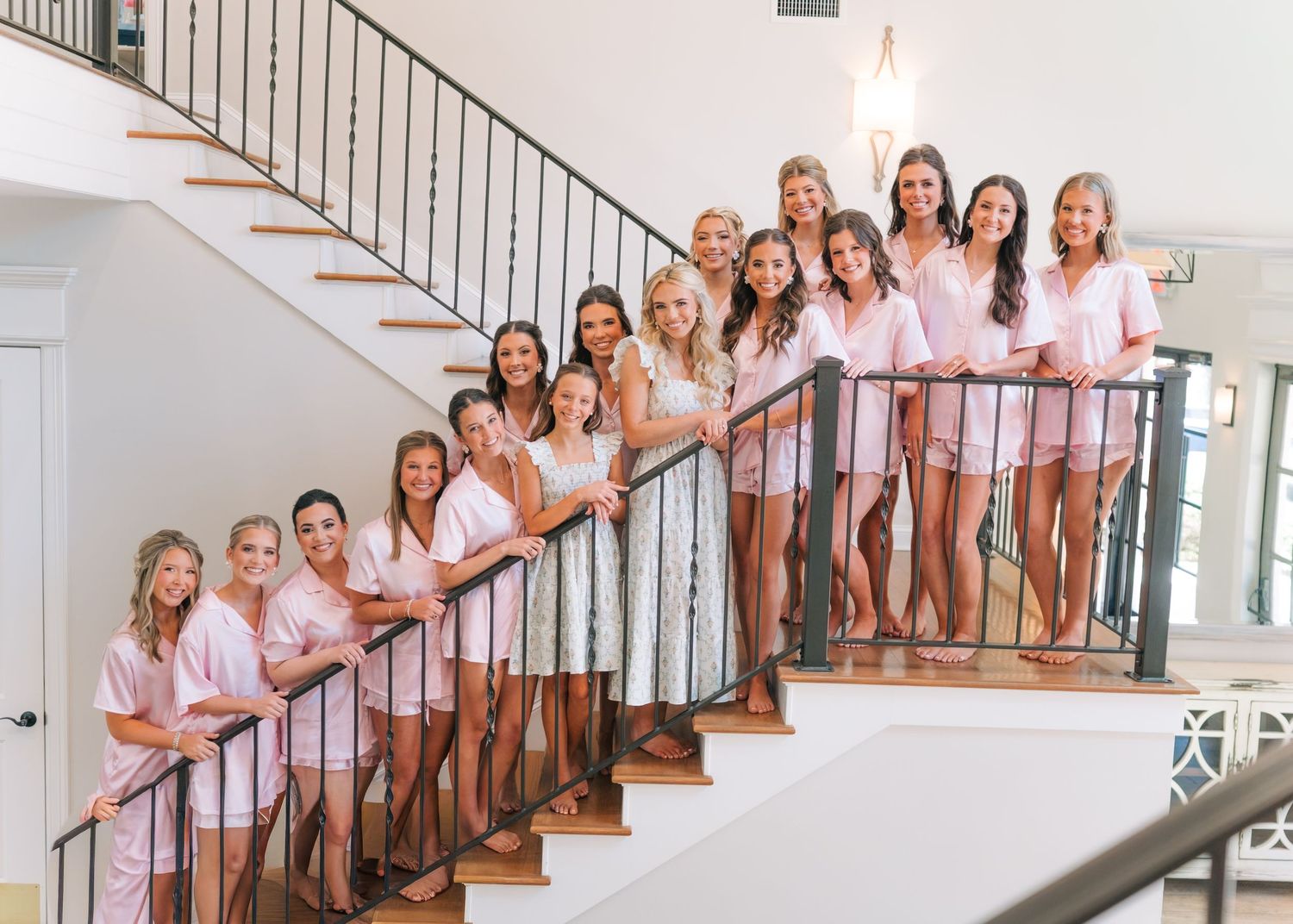 Bride and bridesmaids in pink robes posing on a staircase before the wedding ceremony.