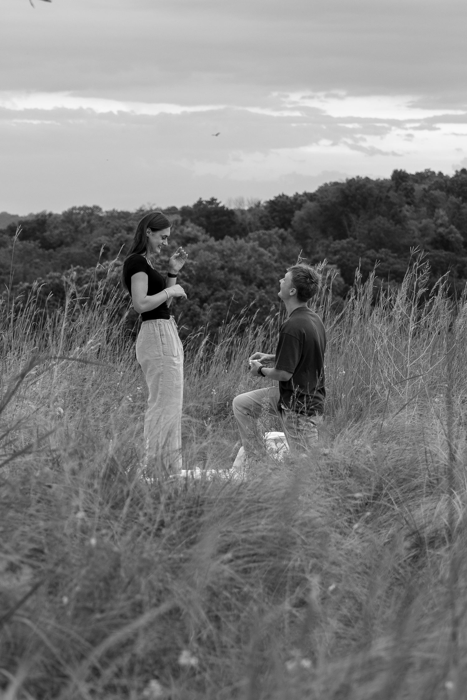 A couple proposal together in an open field during an outdoor engagement session.