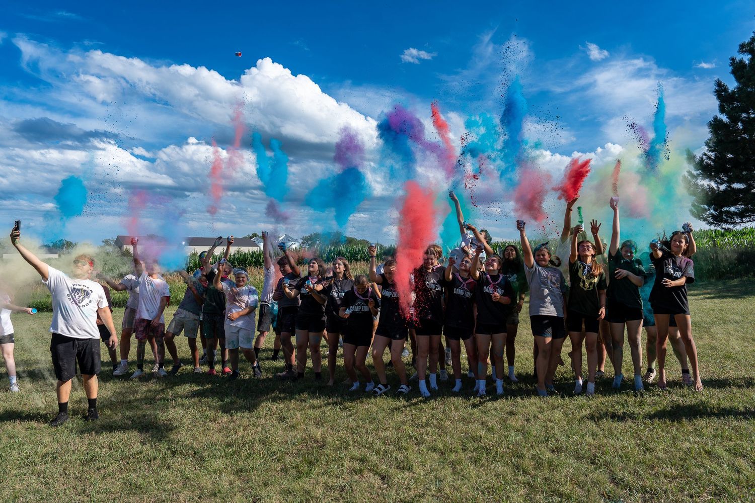 Youth group celebrating with colorful powder during a summer church camp event.