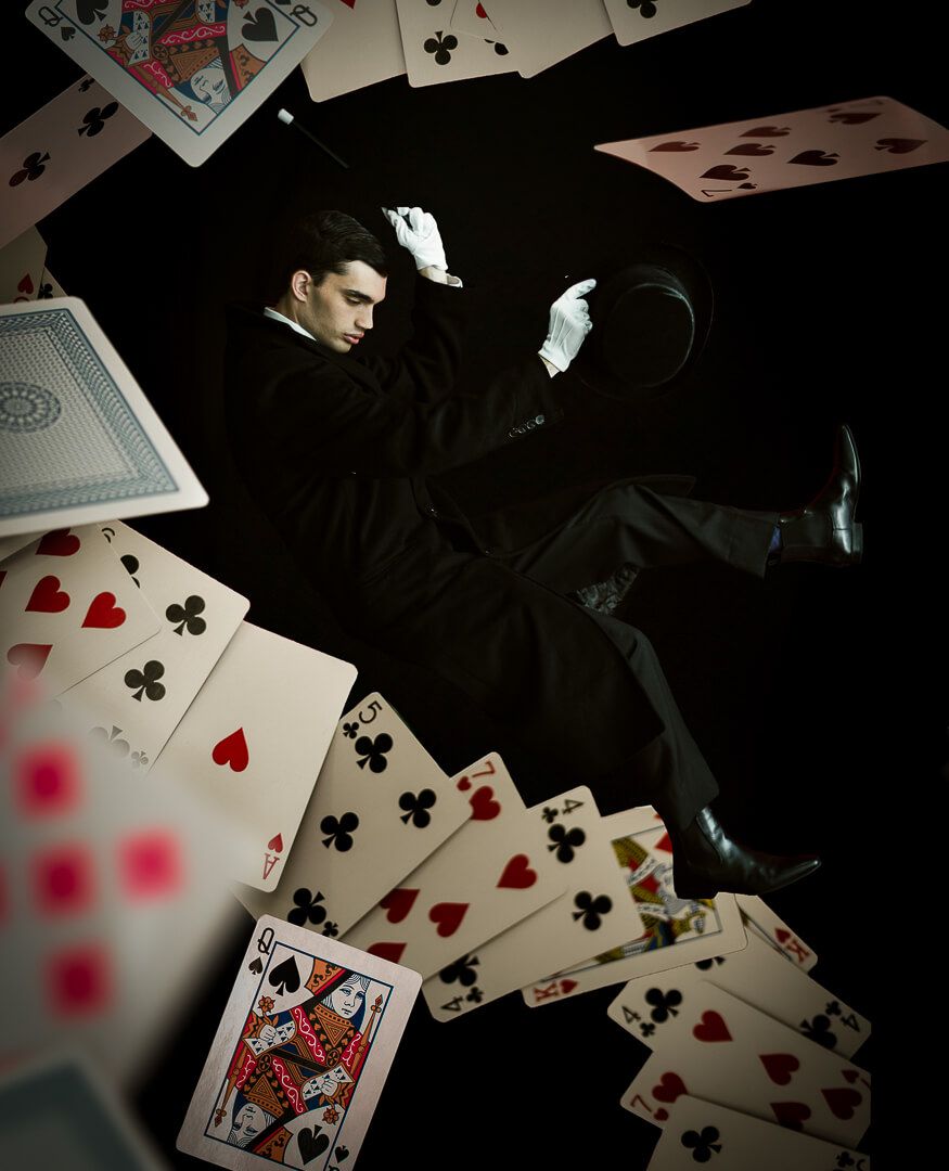 Playing cards scattered across a dark surface with dramatic lighting and shadows creating a moody gambling atmosphere.