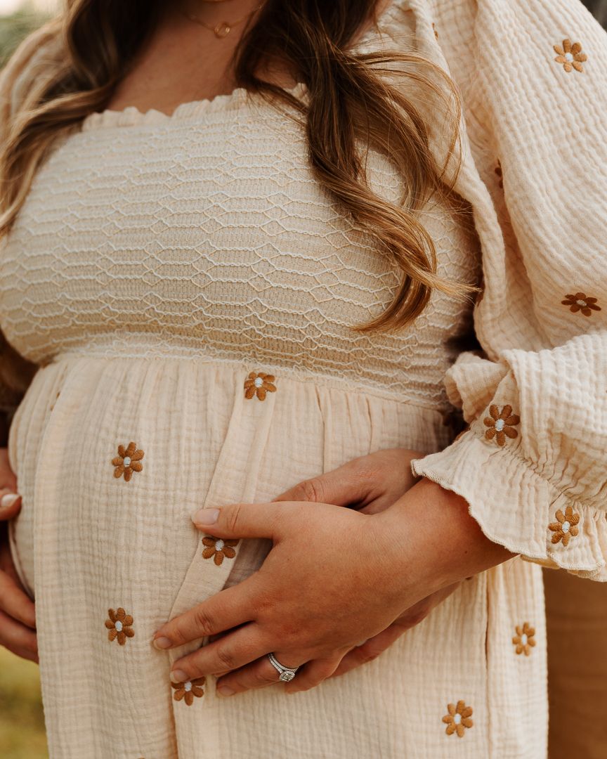 Close-up photos of a pregnant woman's belly in a cream-colored dress with brown floral details.