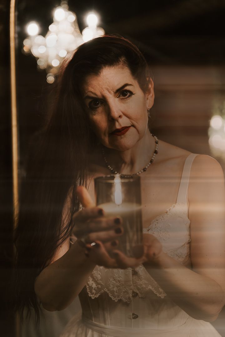 Artistic double exposure portrait creating a dreamy effect with overlapping silhouettes in warm candlelit atmosphere.