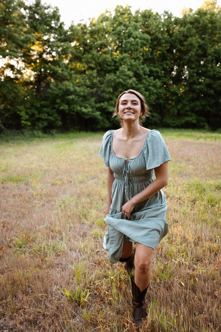 A person in a flowing blue dress explores a serene meadow at golden hour.