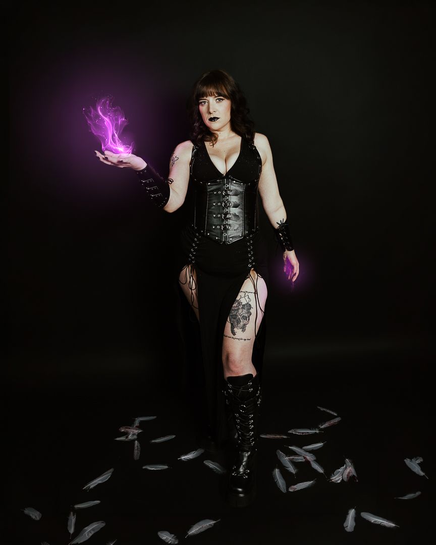 Woman in black corset outfit with knee-high boots holds purple flame, surrounded by white feathers on dark background.