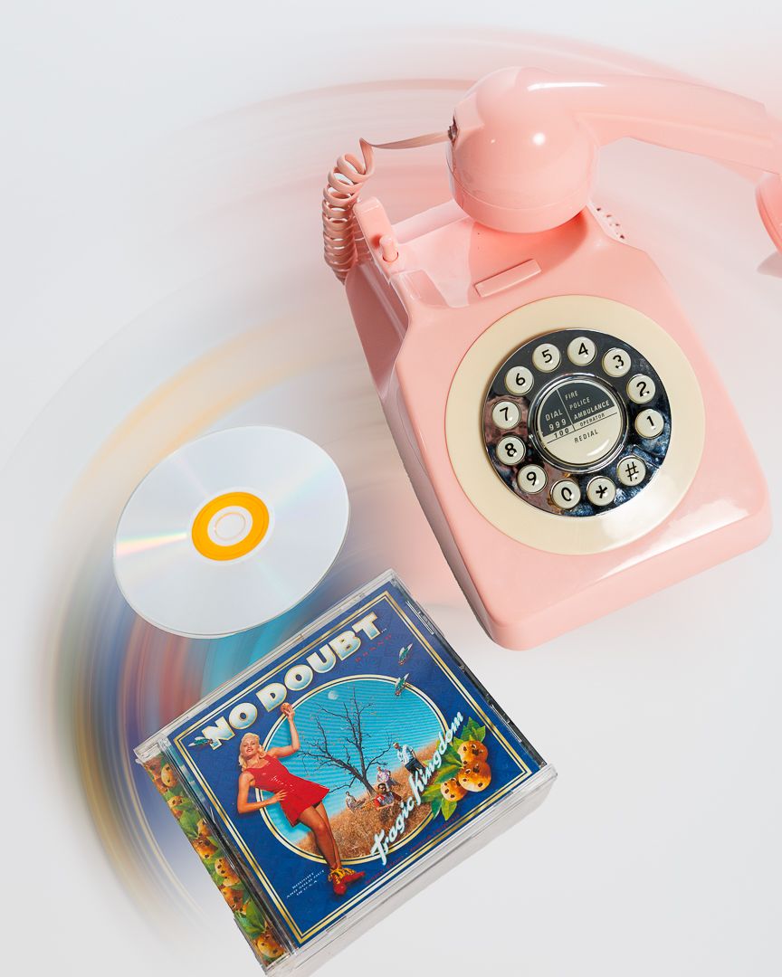 Pink rotary telephone next to vintage postcards on white background showcasing retro nostalgia.