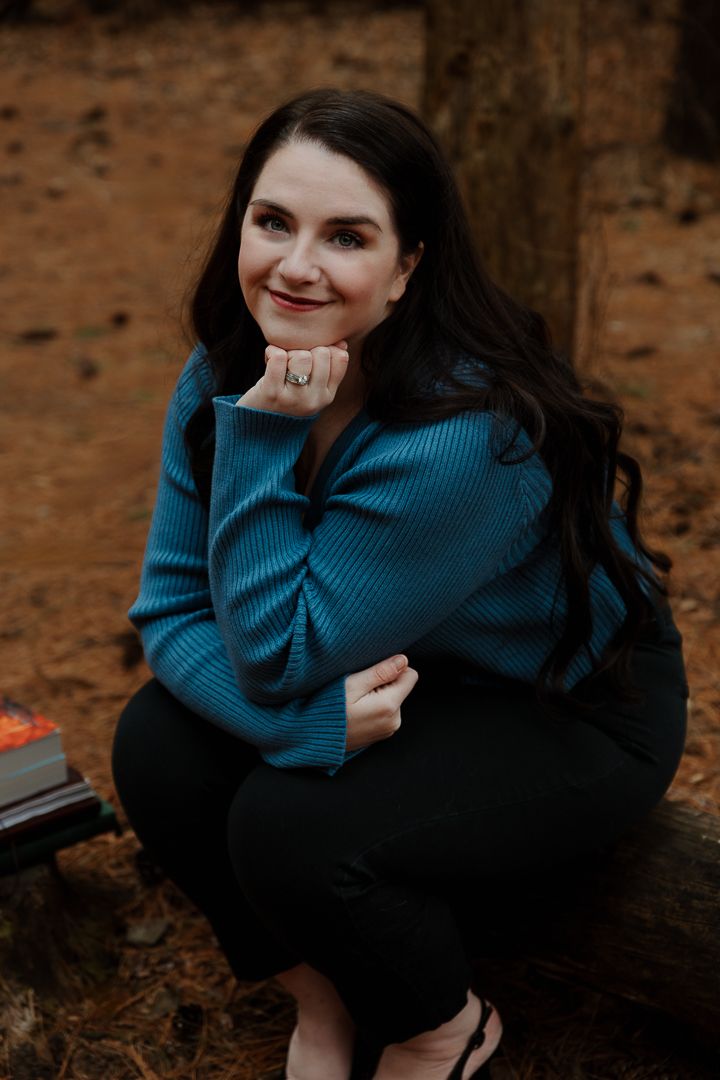 Person in dark blue sweater sits casually for outdoor portrait session.