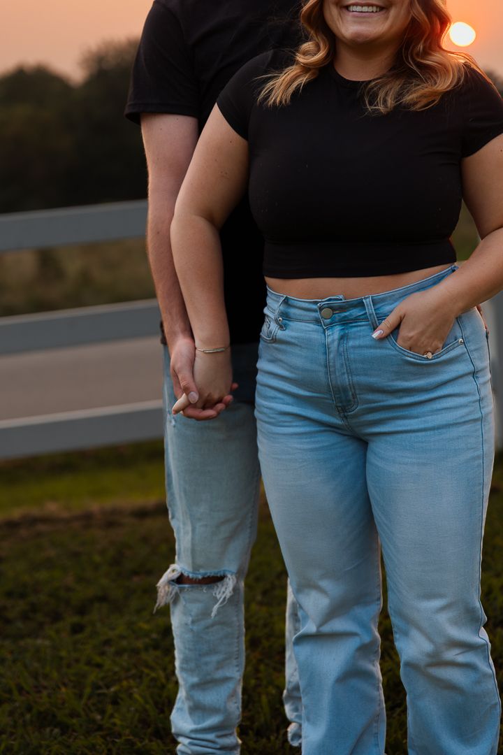 Close-up view of people wearing matching black tops and light blue jeans standing together outdoors.