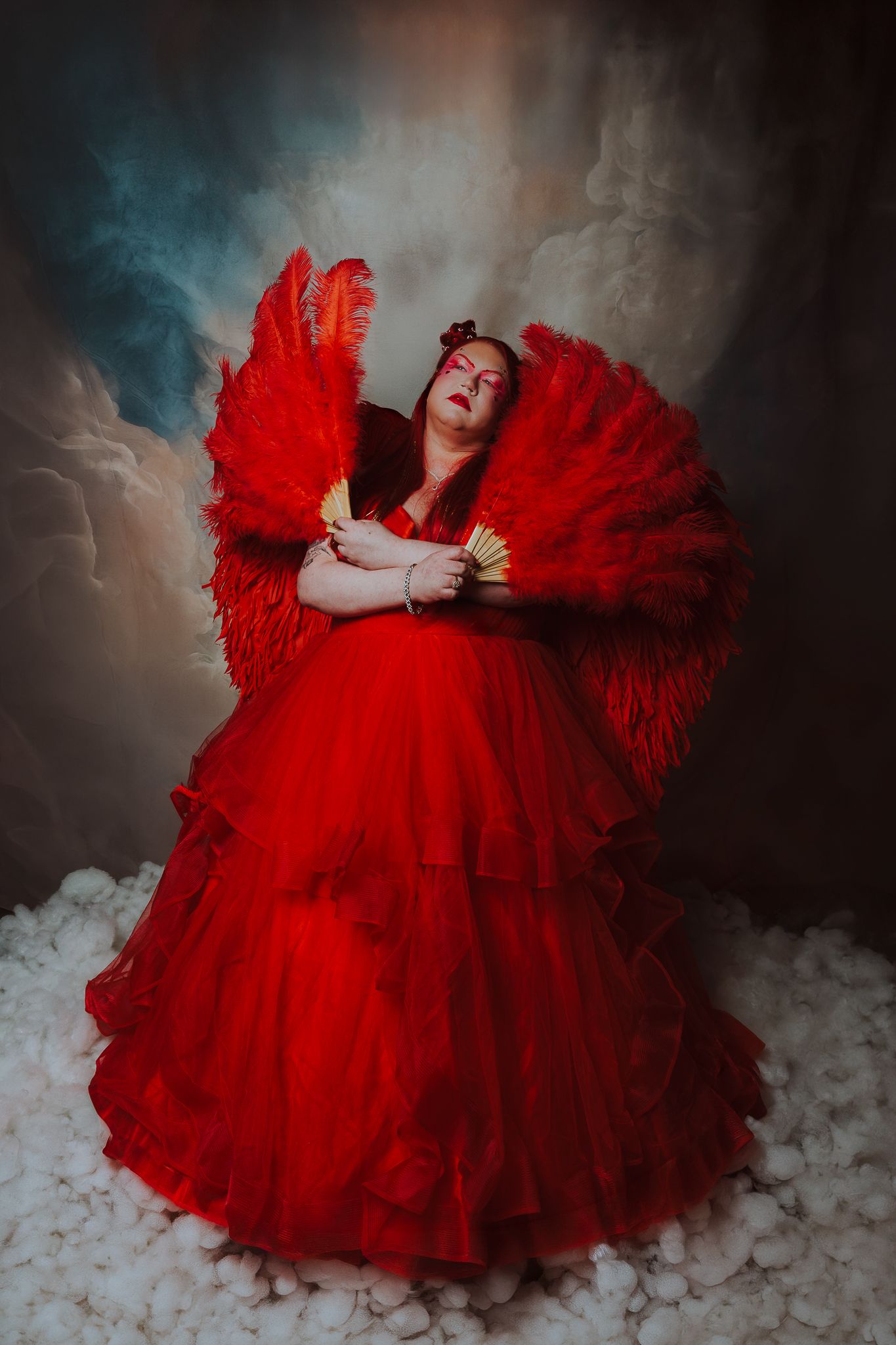 Dramatic portrait in flowing red dress against smoky background.