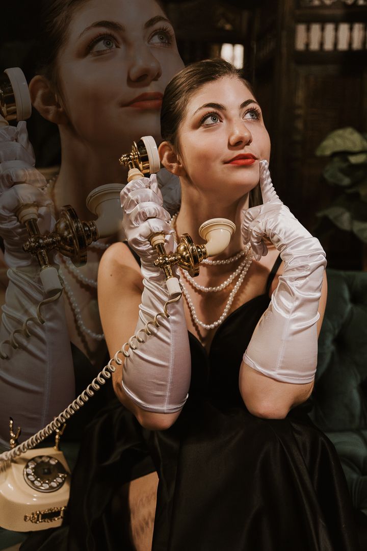 A woman in white gloves and pearl necklace poses with a vintage rotary telephone in a series of dramatic shots.