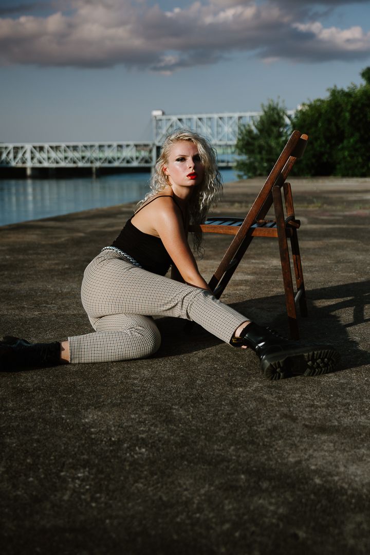 A series of dramatic outdoor fashion portraits taken on a concrete surface with a bridge backdrop at golden hour.