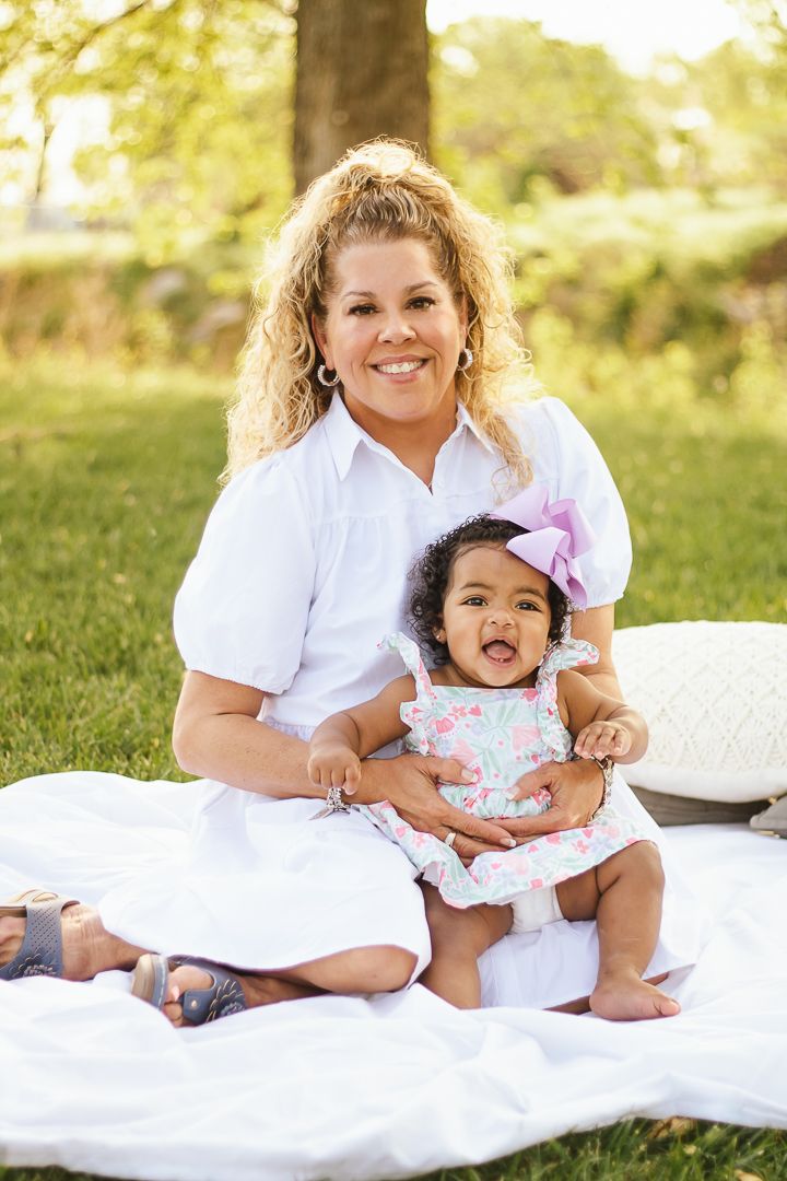 A heartwarming family portrait on a white blanket outdoors with coordinated white outfits.