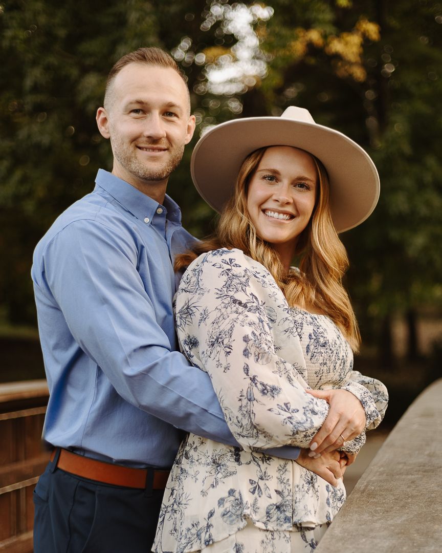 A couple in blue and floral attire share romantic moments during an outdoor photoshoot at sunset.
