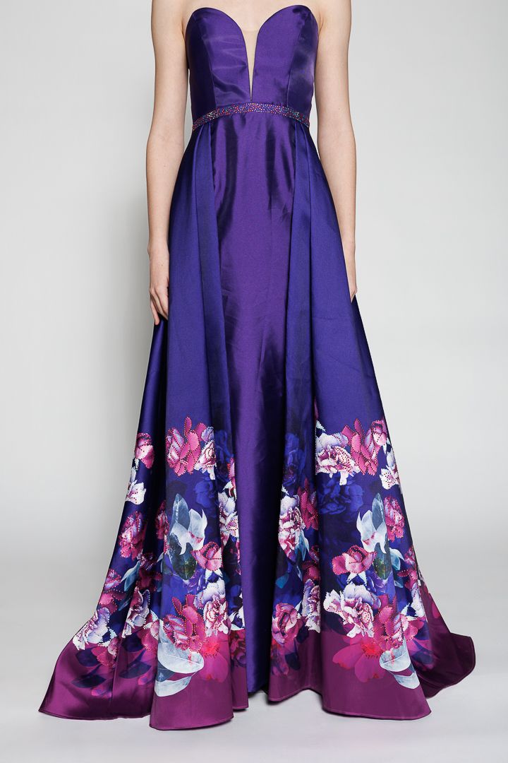 Strapless purple satin ballgown with floral border print in pink and blue, featuring a deep V-neckline and embellished waist.