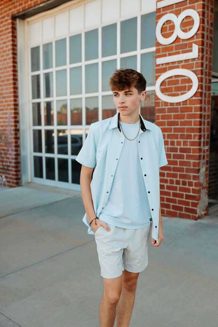 Modern street style portrait against red brick wall showing light colored summer outfit.