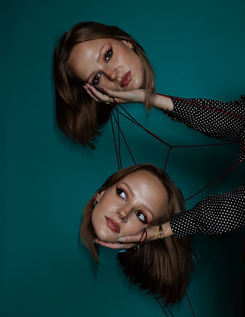 Moody fashion portrait with polka dot pattern clothing against deep teal background in low light.