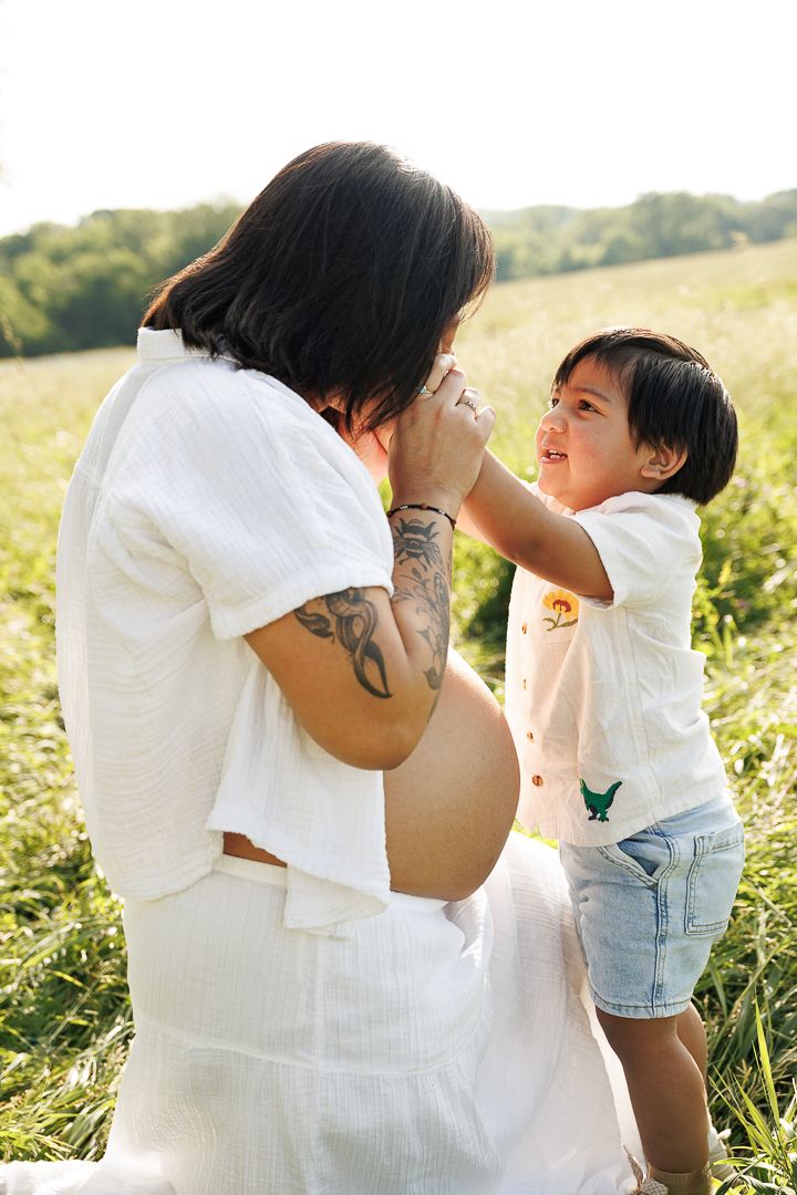 Sweet candid family interactions photographed in a golden-hour meadow setting with natural sunlight.