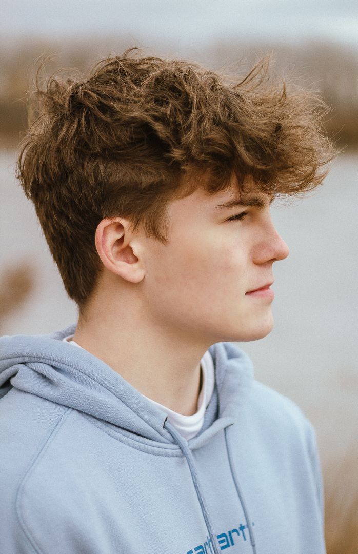 Profile views of person wearing a light gray hoodie against a blurred background.