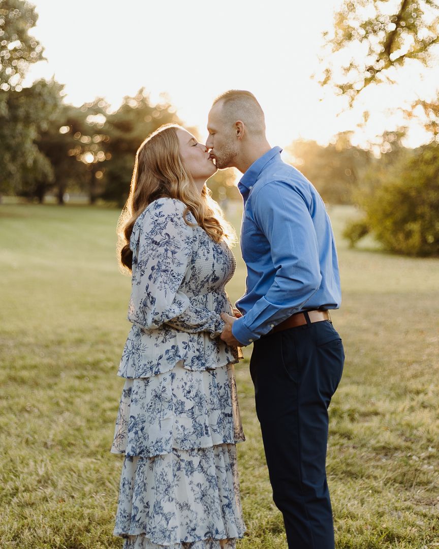 A couple shares an intimate moment in a sun-drenched field during golden hour.