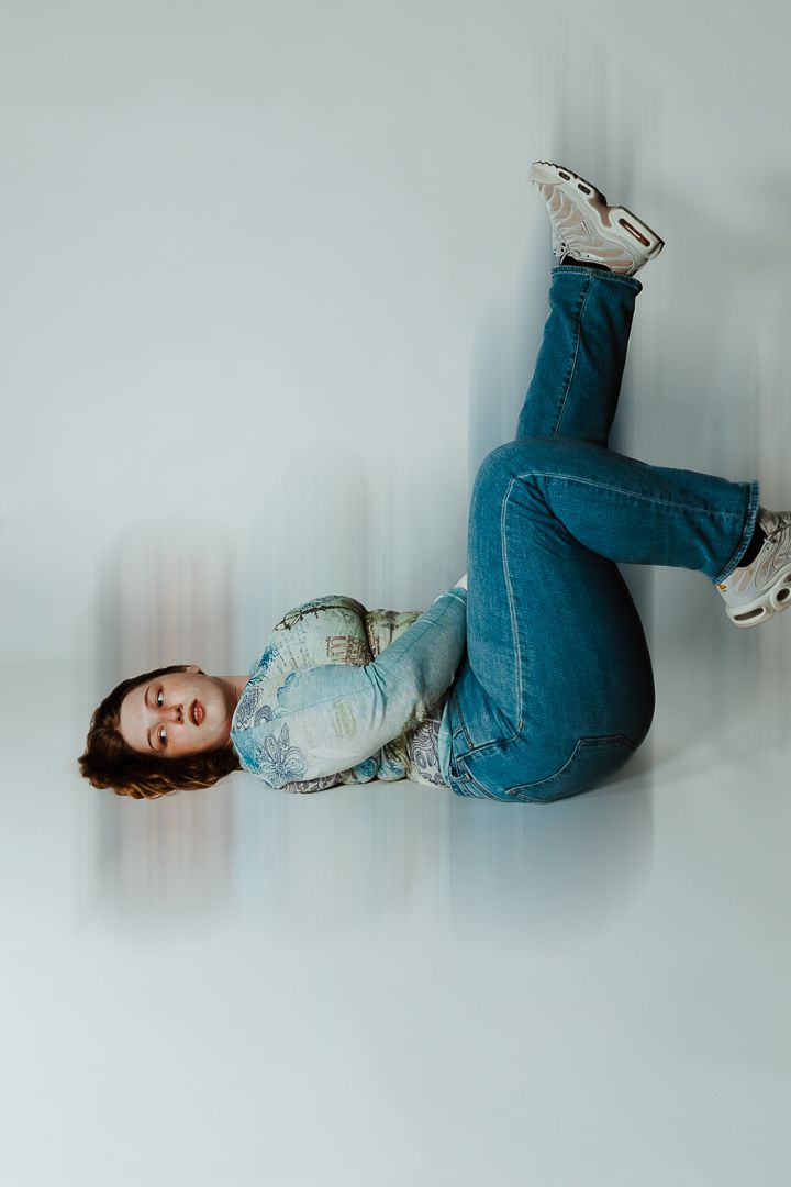 Dreamy minimalist photo series of someone lying on light grey background wearing denim.