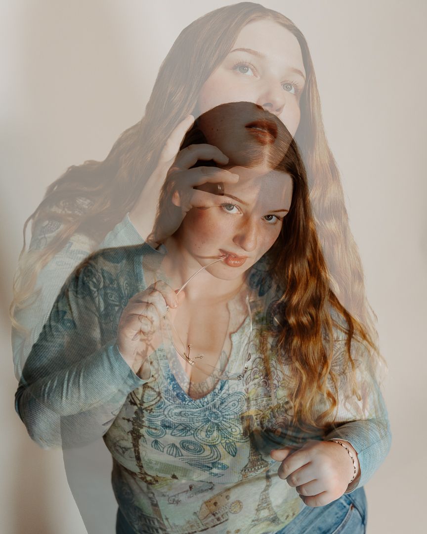 Ethereal double exposure portrait in blue vintage dress with overlapping faces creating dreamy effect.