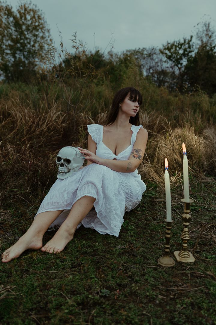 Artistic portrait series in nature featuring white fabric, candlelight, and greenery in moody evening lighting.
