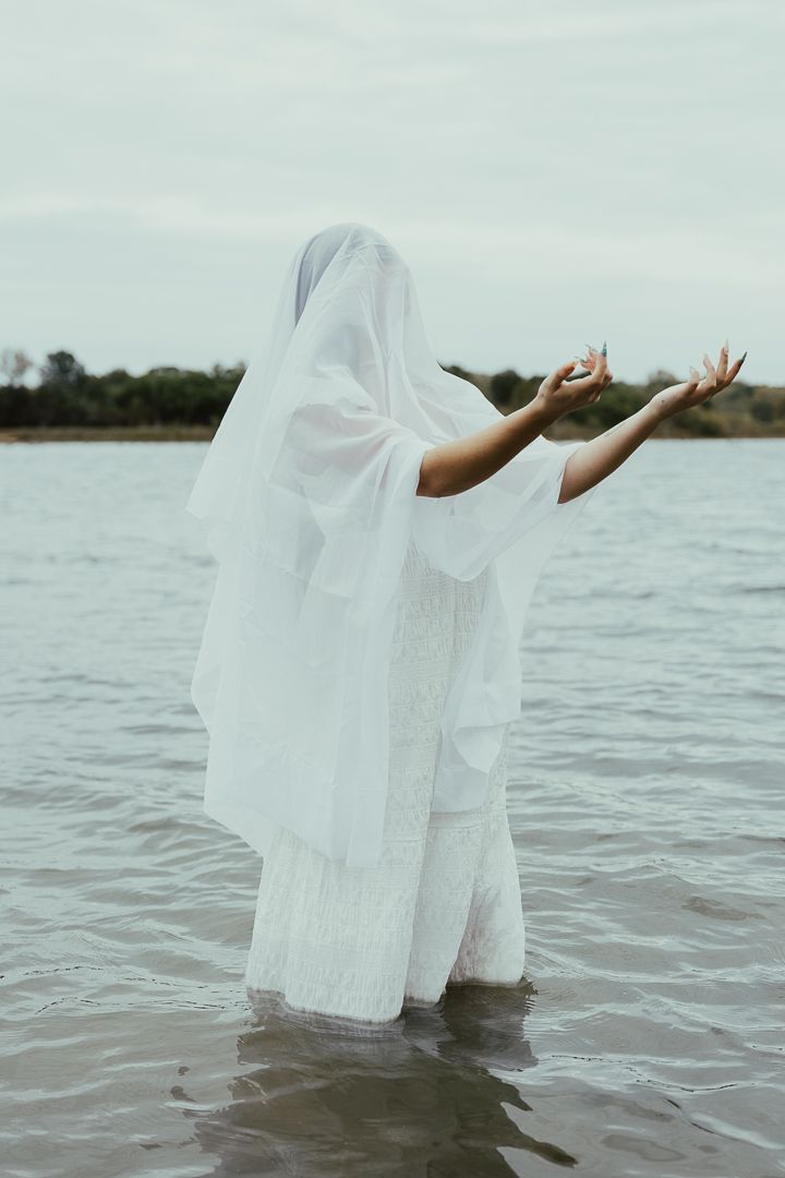 Ethereal scene of white dress floating on lake water in mystical dance-like motion.