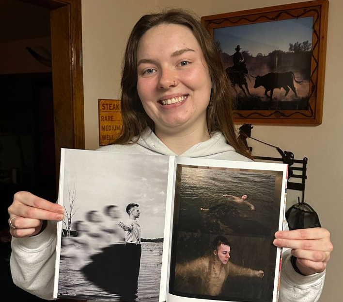 Person displaying black and white photographic prints in home setting.
