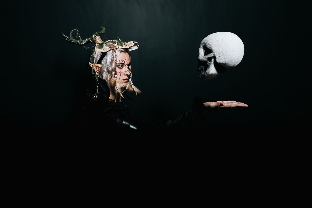 A dramatic dark artistic photograph showing a severed hand holding a white skull against a black background.