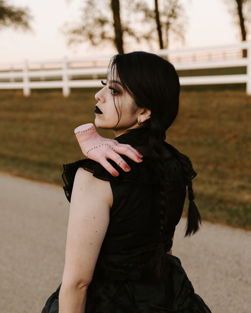 A person in a black hoodie is shown from behind with their hair in braids against a blurred outdoor background.