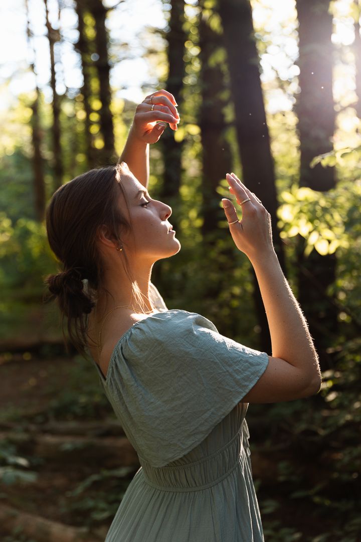 A person in a light blue dress poses against a sunlit woodland backdrop in a series of images.