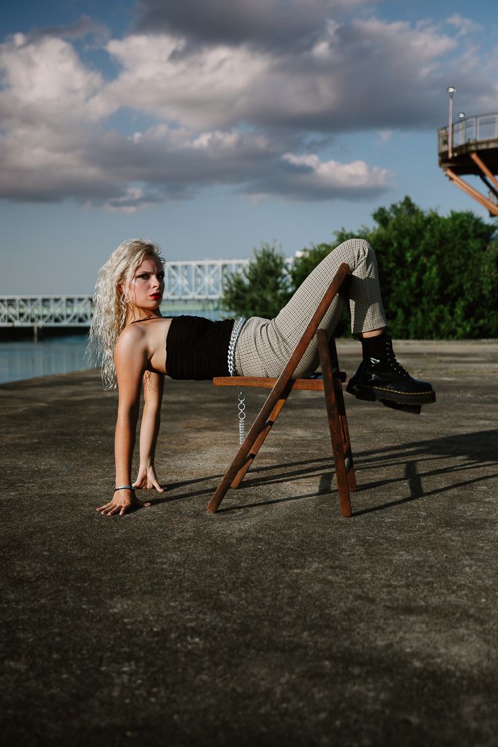 A creative photo series showing different angles of someone posing on a wooden chair against a cloudy sky backdrop.