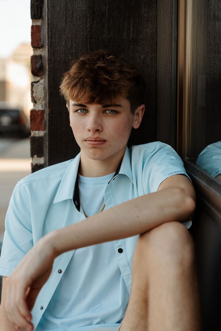 A person wearing a light blue polo shirt sits casually near a brick wall in a series of similar portrait poses.