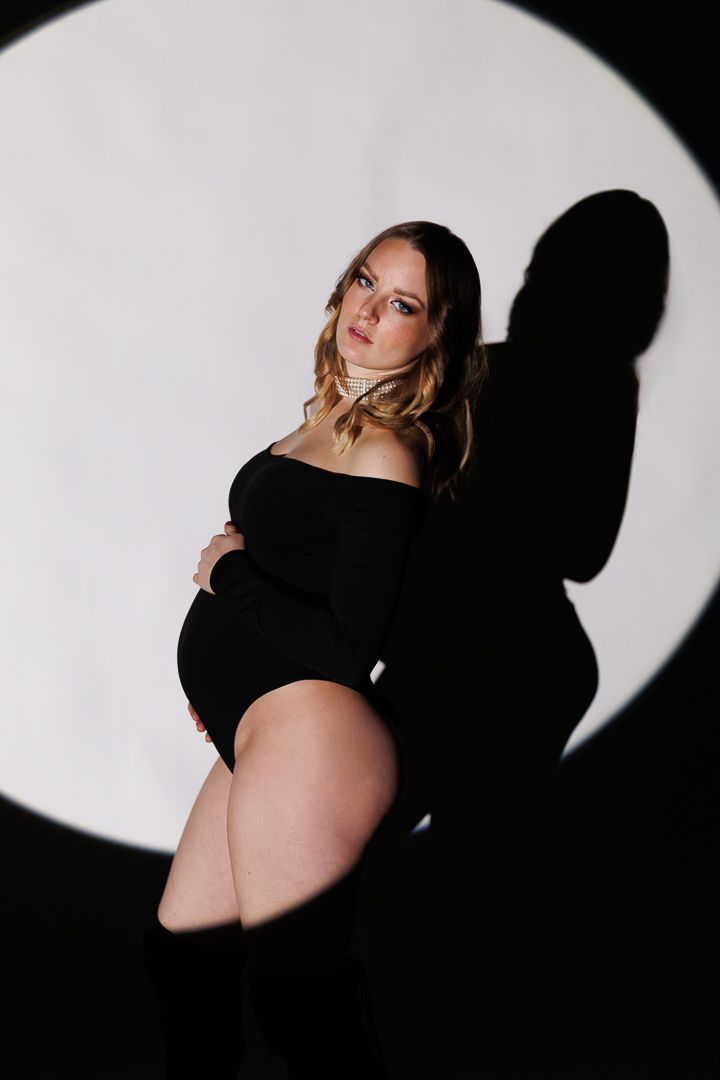 Dramatic silhouetted maternity photo series showing pregnant belly against stark black and white circular lighting.