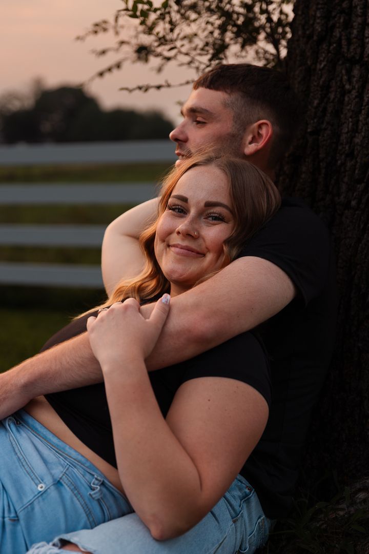 Romantic sunset moment as couple shares intimate embrace against tree silhouette backdrop.