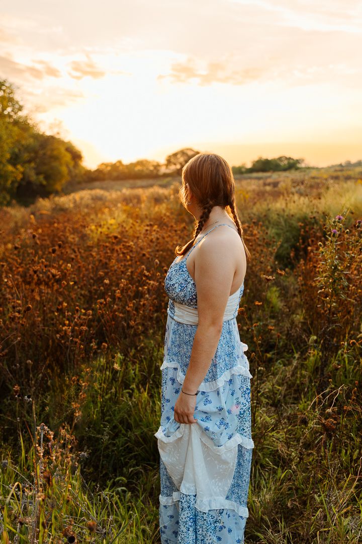 A blue floral dress catches the warm evening light in a field of autumn wildflowers.