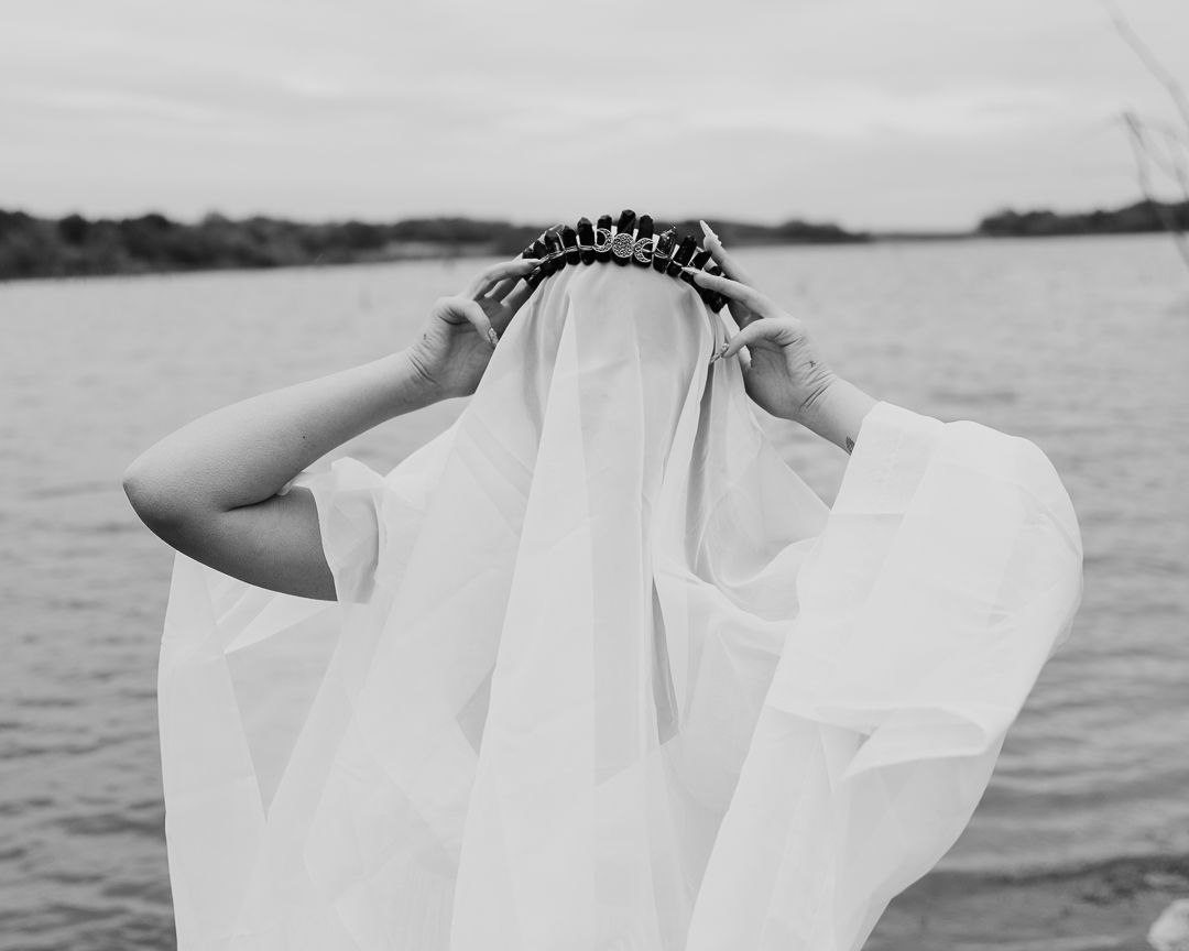 Flowing white fabric creates an ethereal silhouette against a serene waterscape.