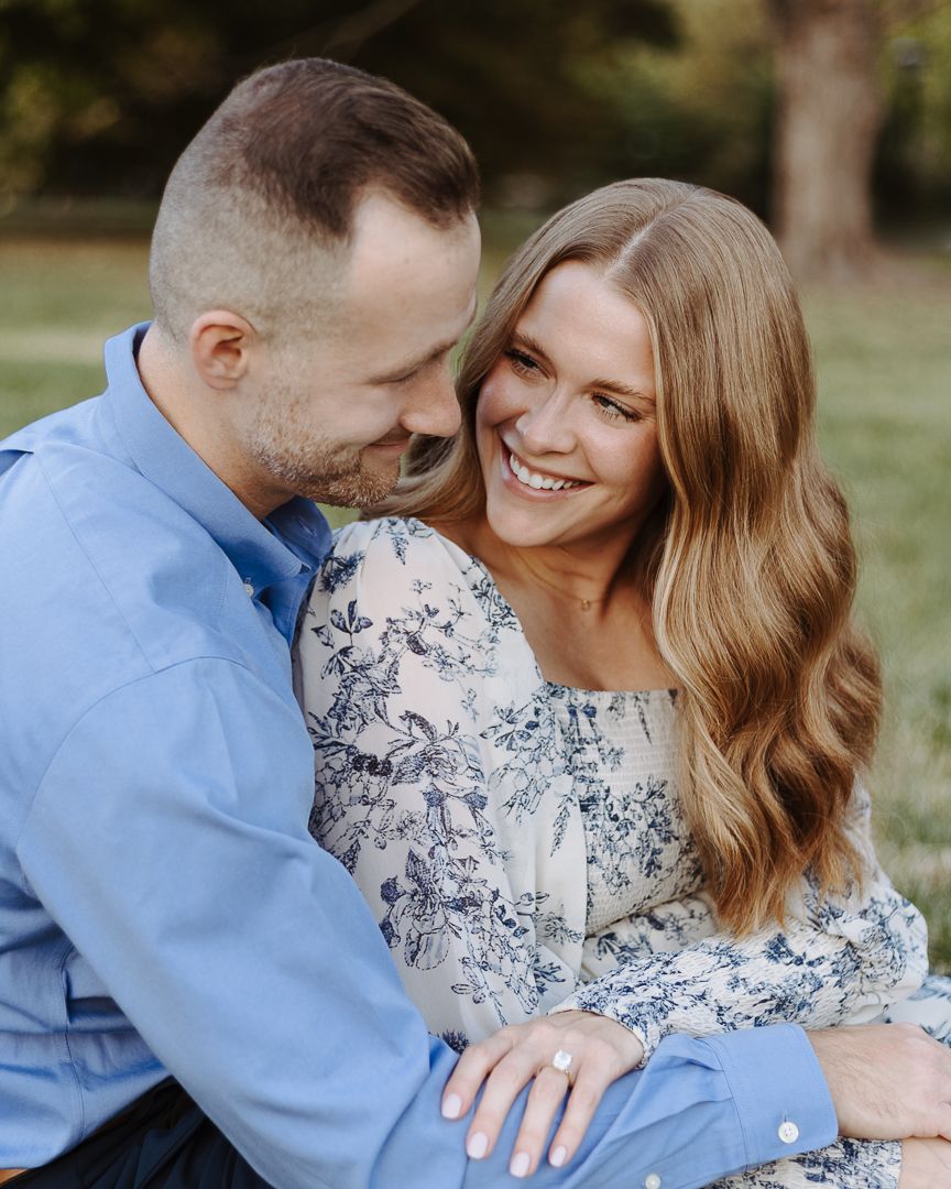 Romantic couple shares tender moments during outdoor photo session wearing blue and floral outfits.