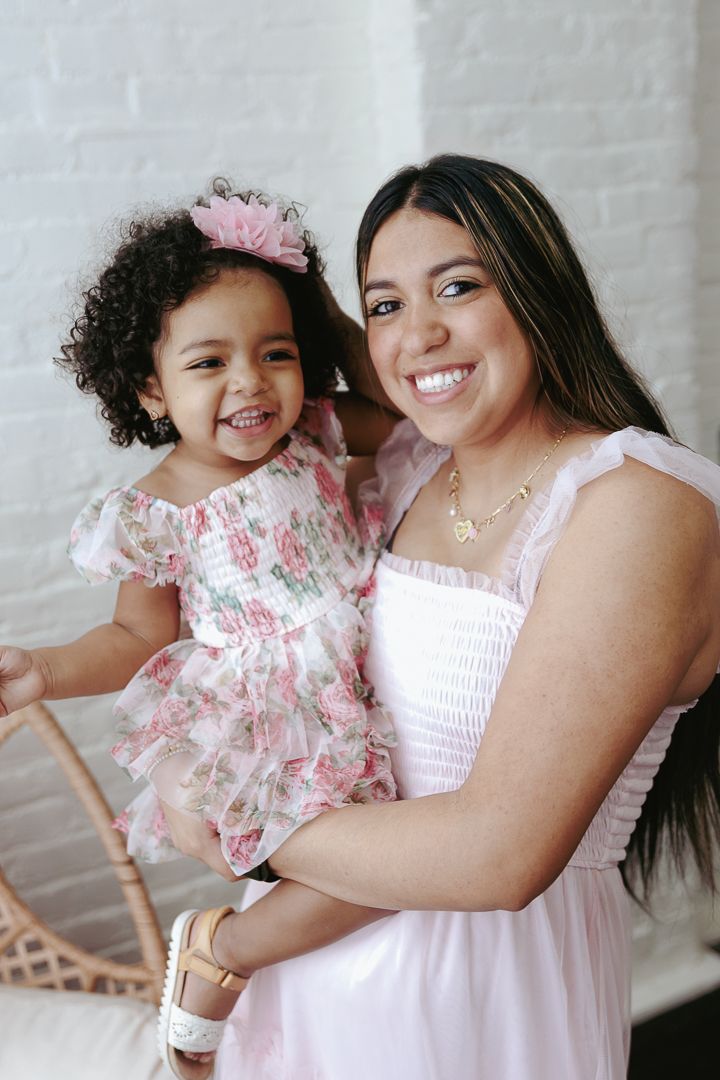 Mother and daughter wearing matching pink dresses share joyful moments in a photo series.