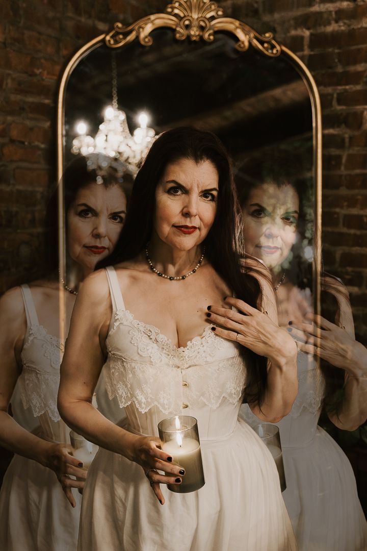 A moody and artistic multiple exposure portrait showing ethereal overlapping figures in white lace against a brick wall.