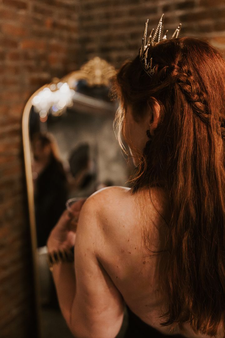 Artistic boudoir photo showing bare shoulders against brick wall background.