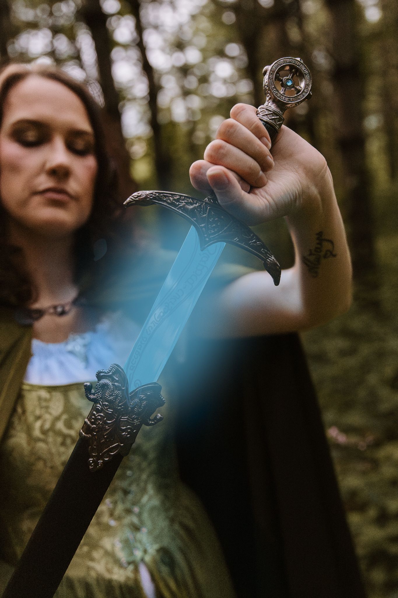 Woman in medieval dress holding an ornate glowing sword in a forest, fantasy cosplay photography.