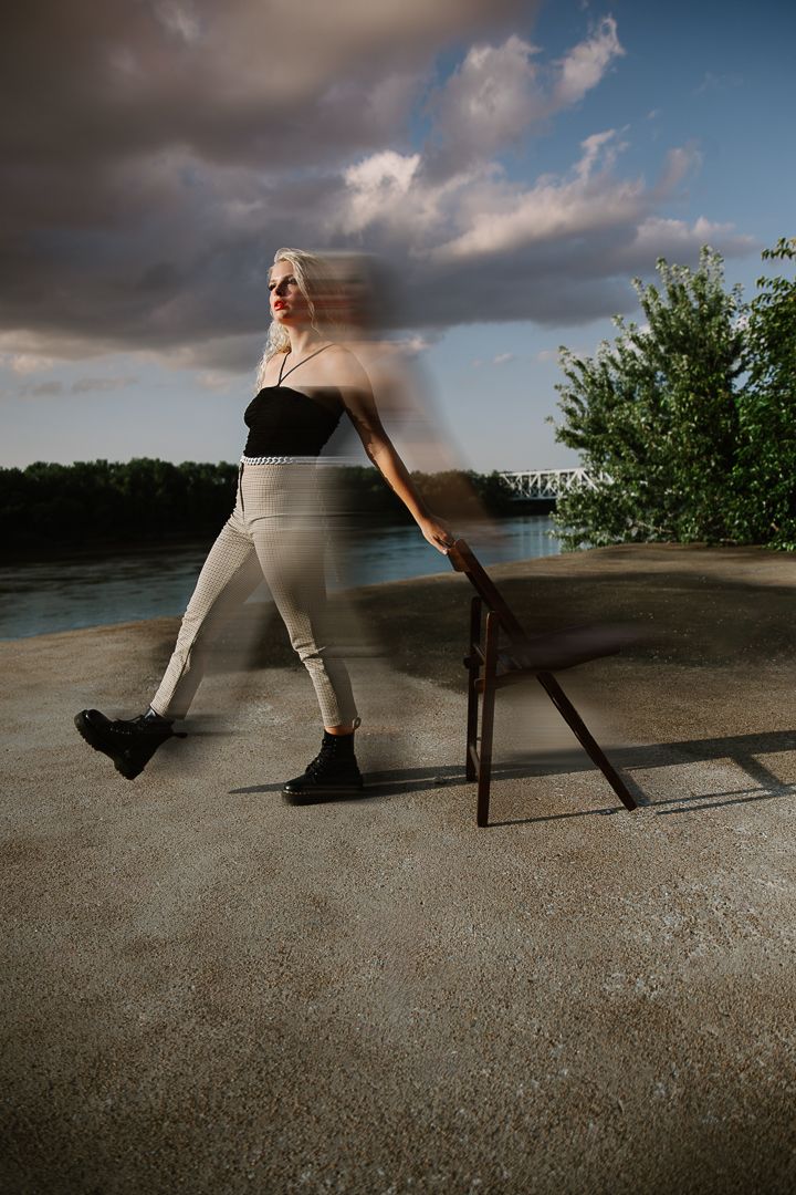 Motion blur sequence shows figure in athletic pose performing skateboard trick on concrete surface near water.