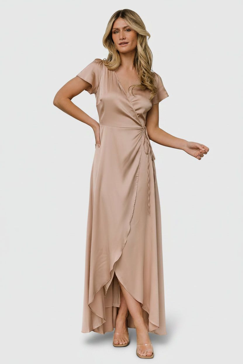 Woman wearing a champagne satin wrap maxi dress with short sleeves and ruffle hem detail.