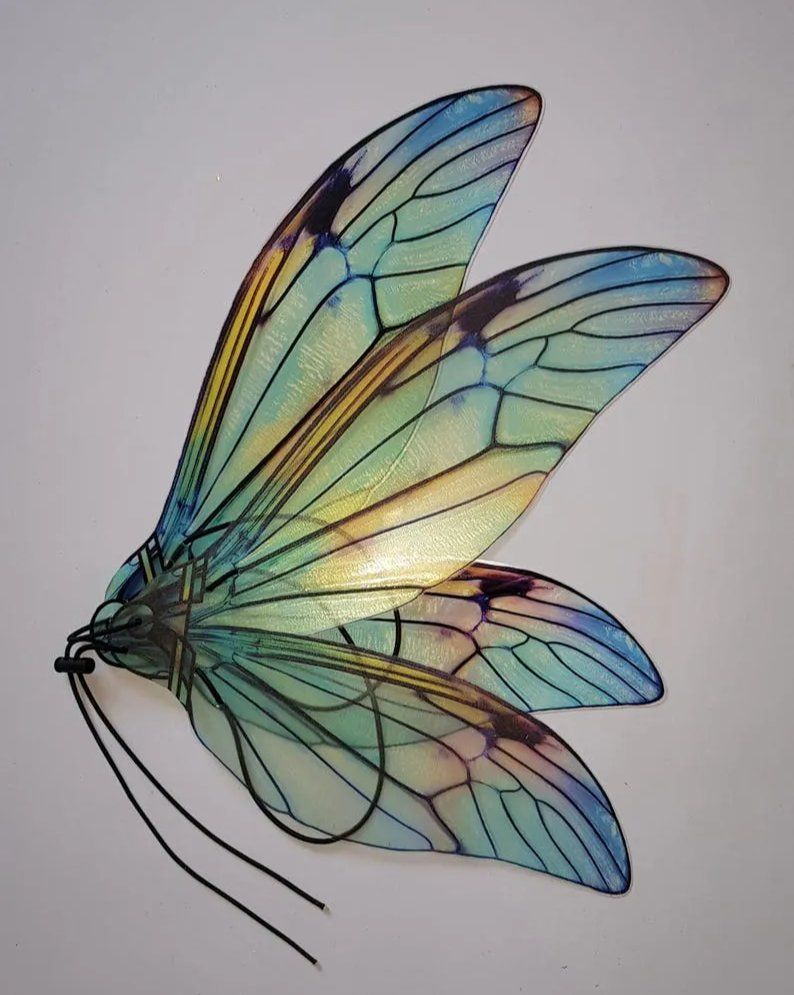 Iridescent handmade fairy wings with delicate dark veining and blue, green and gold translucent colors, shown with black elastic straps.