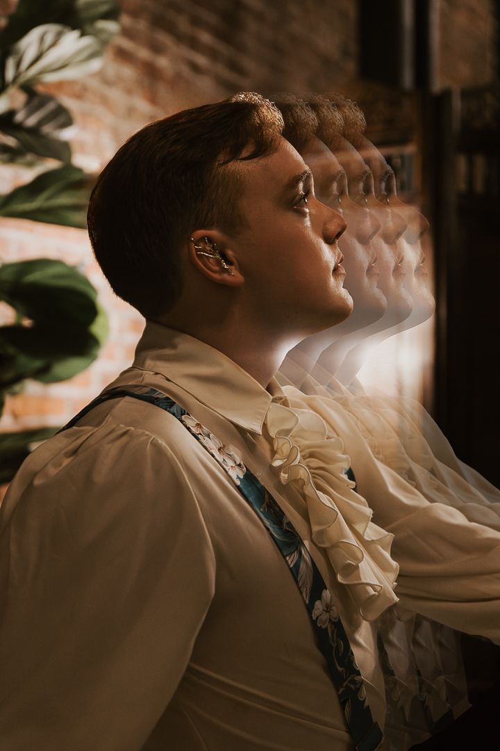 A profile view portrait in sepia tones shows a person wearing a white ruffled shirt and dark suspenders.