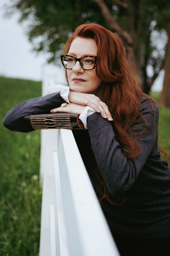 Artistic portrait series of a person in glasses leaning on a white railing in an outdoor garden setting.